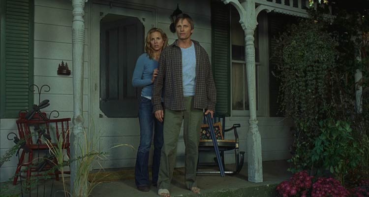 A History of Violence 2005 Movie Scene Viggo Mortensen as Tom Stall holding a shotgun in front of his house with Maria Bello as Edie standing next to him