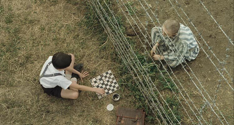 The Boy in Striped Pajamas 2008 Movie Scene Asa Butterfield as Bruno playing chess with Jack Scanlon as Shmuel as they're separated by the barb wire of the concentration camp