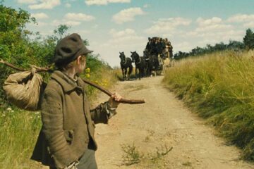 Oliver Twist 2005 Movie Scene Barney Clark as Oliver Twist walking down the country road with a carriage behind him