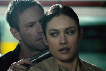 Erased 2012 Movie Scene Aaron Eckhart as Ben Logan holding a gun to Olga Kurylenko as Anna Brandt's head