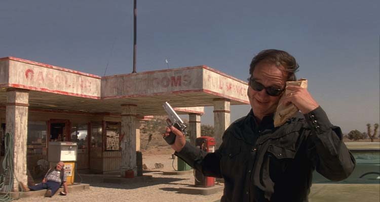 Retroactive 1997 Movie Scene Jim Belushi as Frank holding a gun in front of a gas station