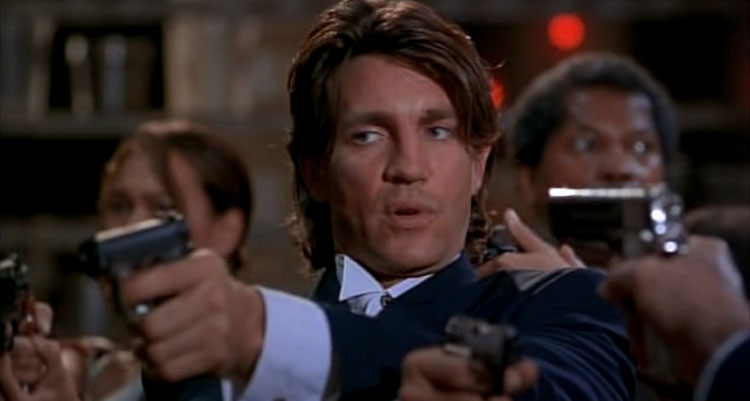 The Immortals 1995 Movie Scene Eric Roberts as Jack holding two guns with Tia Carrere and Clarence Williams III in the background in the kitchen