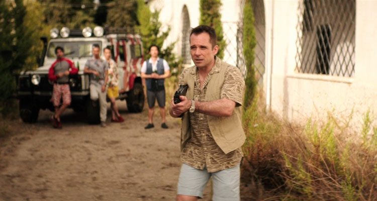 The Rezort Movie 2015 Scene Tourist holding a machine gun and waiting for zombies to pop out while the rest of the group is waiting by the jeep