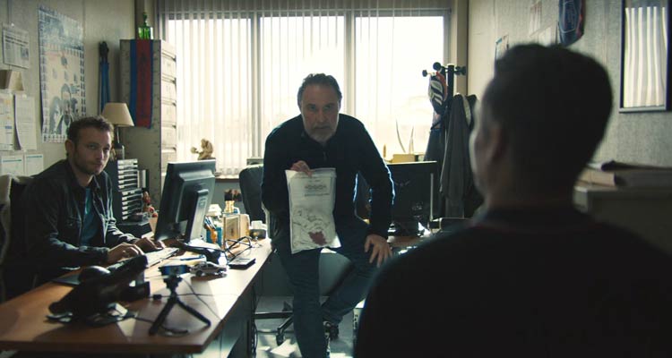 The Night of the 12th 2022 Movie Scene Bouli Lanners as Marceau holding a bloody shirt while questioning the suspect