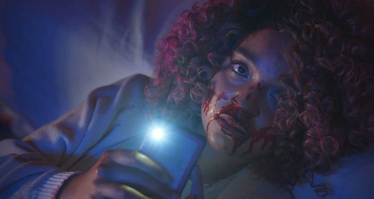 Sissy 2022 Movie Scene Aisha Dee as Cecilia holding her phone and filming the murder with a bloody face