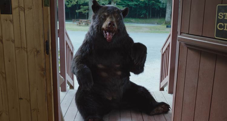 Cocaine Bear 2023 Movie Scene A black bear high on cocaine sitting playfully next to the door