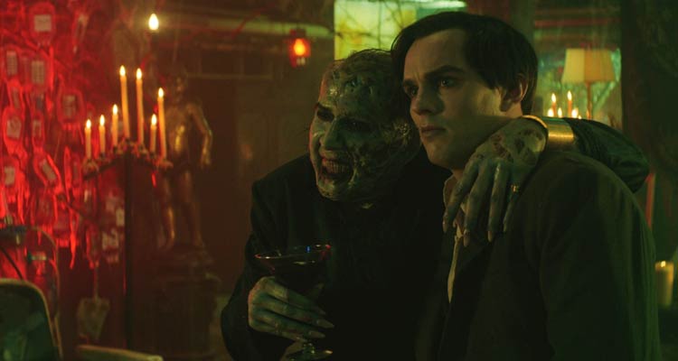 Renfield 2023 Movie Scene Nicholas Hoult as Renfield and Nicolas Cage as Dracula talking in his lair while he's drinking blood