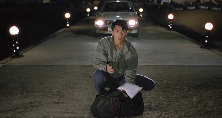 Tiger Cage 1988 Movie Scene Donnie Yen as Terry holding a gun and a bag of cocaine on the pier