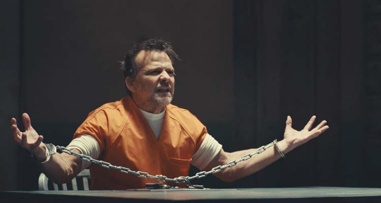 Nefarious 2023 Movie Scene Sean Patrick Flanery as Nefarious AKA Edward Wayne Brady in an orange prison jumpsuit in handcuffs spreading his arms