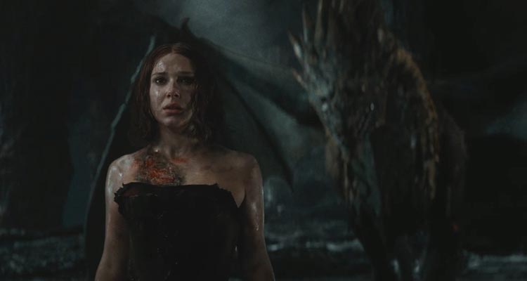 Damsel 2024 Movie Scene Millie Bobby Brown as Elodie in the cave with the dragon slowly sneaking up on her in the background