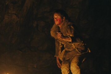 Out of Darkness 2022 Movie Scene Safia Oakley-Green as Beyah all bloody, holding a knife and hiding in a cave