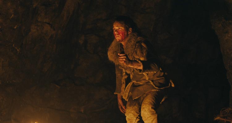 Out of Darkness 2022 Movie Scene Safia Oakley-Green as Beyah all bloody, holding a knife and hiding in a cave