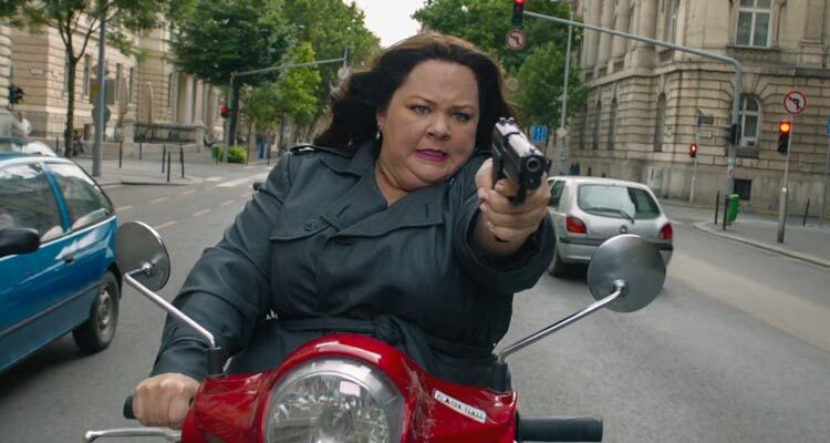 Spy 2015 Movie Scene Melissa McCarthy as Susan Cooper holding a gun while driving a scooter