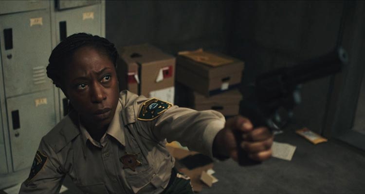 Jericho Ridge 2023 Movie Scene Nikki Amuka-Bird as Deputy Tabby Temple holding a gun pointed at the intruder in the police station