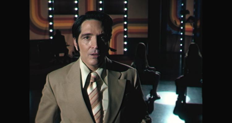 Late Night With The Devil 2023 Movie Scene David Dastmalchian as Jack Delroy announcing his guests, a demonically possessed girl and her doctor