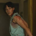 Love Lies Bleeding 2024 Movie Scene Kristen Stewart as Lou covered in blood after Jackie shot Daisy