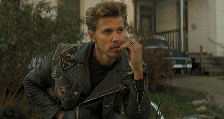 The Bikeriders 2023 Movie Austin Butler as Benny smoking a cigarette and wearing a leather jacket while sitting on his motorcycle