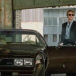 The Driver 1978 Movie Scene Ryan O'Neal as The Driver shooting over his car, a black 1977 Pontiac Firebird Esprit