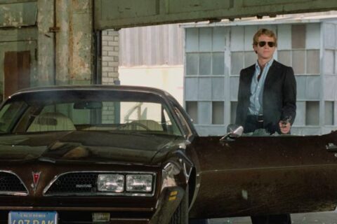 The Driver 1978 Movie Scene Ryan O'Neal as The Driver shooting over his car, a black 1977 Pontiac Firebird Esprit