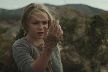 The King Tide 2023 Movie Scene Alix West Lefler as Isla with bees on her hand on the island