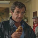 The Professional 1981 Movie Scene Jean-Paul Belmondoas Joss Beaumont holding a croissant as a weapon