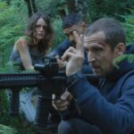 Ad Vitam 2025 Movie Scene Guillaume Canet as Franck holding a machinegun in the bushes with Stéphane Caillard as Leo and Nassim Lyes as Ben