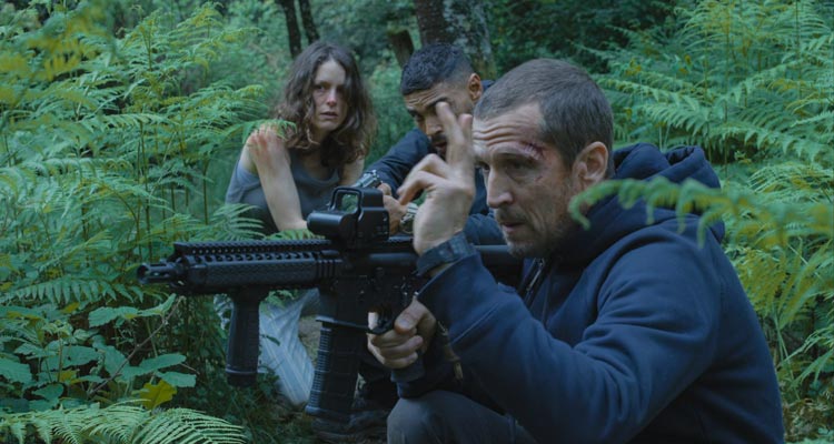 Ad Vitam 2025 Movie Scene Guillaume Canet as Franck holding a machinegun in the bushes with Stéphane Caillard as Leo and Nassim Lyes as Ben