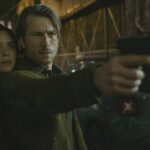 Hit Man 2023 Movie Scene Adria Arjona as Madison Figueroa Masters and Glen Powell as Gary Johnson in an alley holding a gun