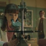 Joy 2024 Movie Scene Thomasin McKenzie as Jean Purdy looking through the microscope during the IVF research
