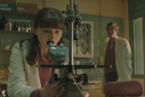 Joy 2024 Movie Scene Thomasin McKenzie as Jean Purdy looking through the microscope during the IVF research