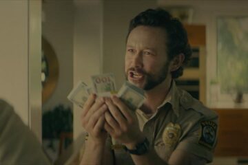 Greedy People 2024 Movie Scene Joseph Gordon-Levitt as Terry holding wads of cash in his hands to his partner