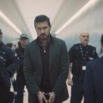 Red Eye 2024 Series Scene Richard Armitage as Dr. Matthew Nolan in handcuffs at the airport escorted by Jing Lusi as DC Hana Li