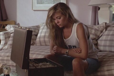 Impulse 1990 Movie Scene Theresa Russell as Lottie Mason in a white shirt looking at a suitcase full of money