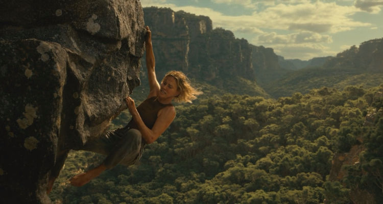 Apex 2026 Movie Scene Charlize Theron as Sasha hanging on the edge of the cliff