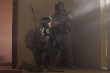 Warfare 2025 Movie Scene D'Pharaoh Woon-A-Tai as Ray and Will Poulter as Erik standing next to the front door calling for backup armed with M4A1 Carbines