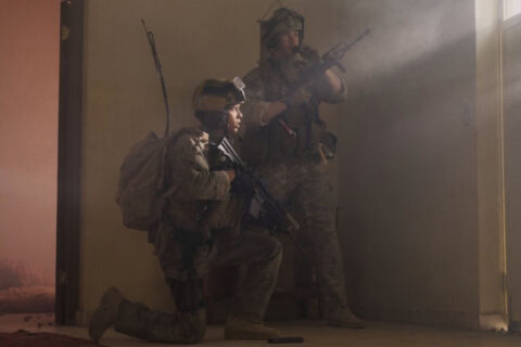Warfare 2025 Movie Scene D'Pharaoh Woon-A-Tai as Ray and Will Poulter as Erik standing next to the front door calling for backup armed with M4A1 Carbines
